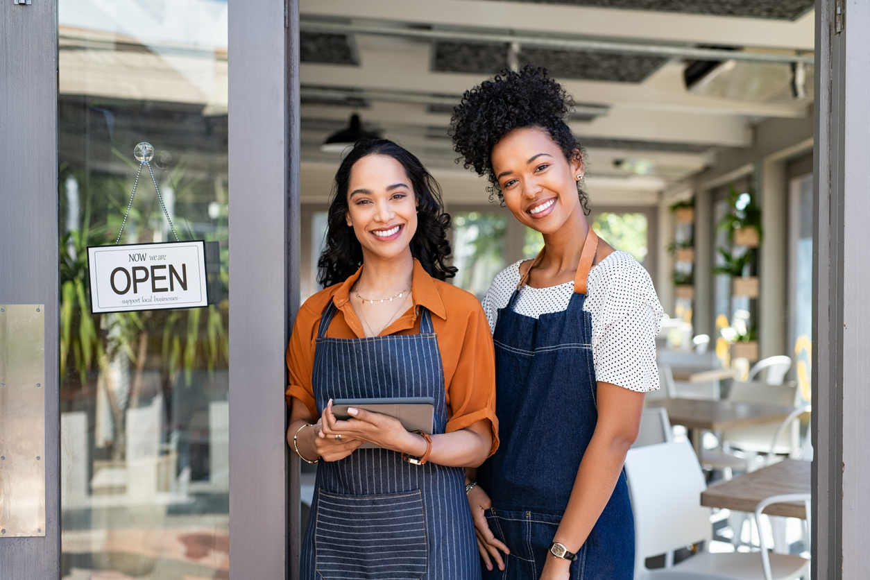 Two small business owners standing outside their shop